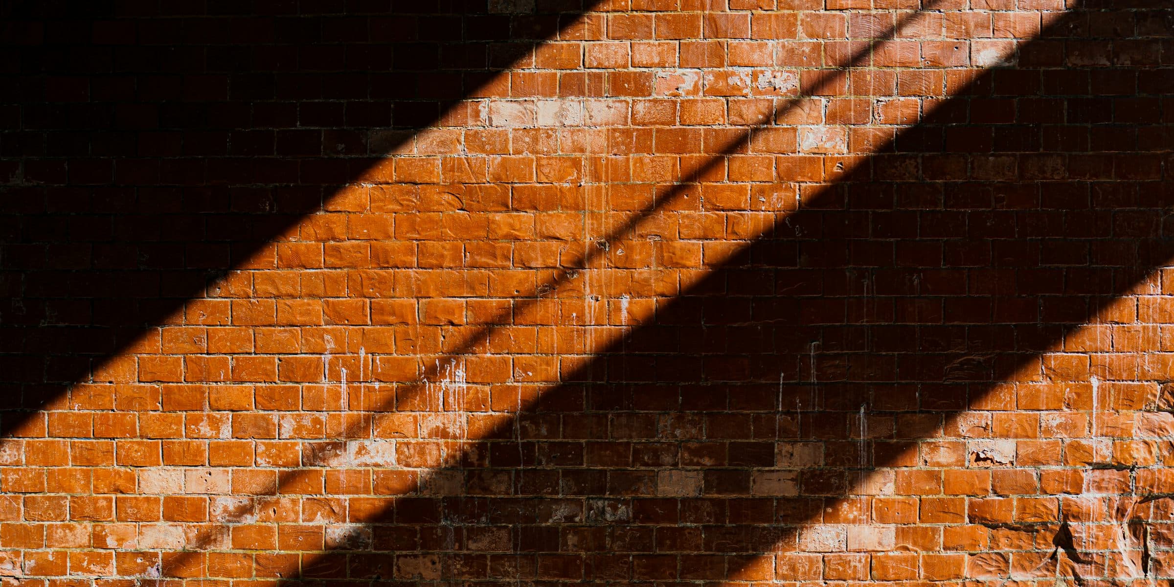 Low sun casting diagonal shadows across an orange brick wall
